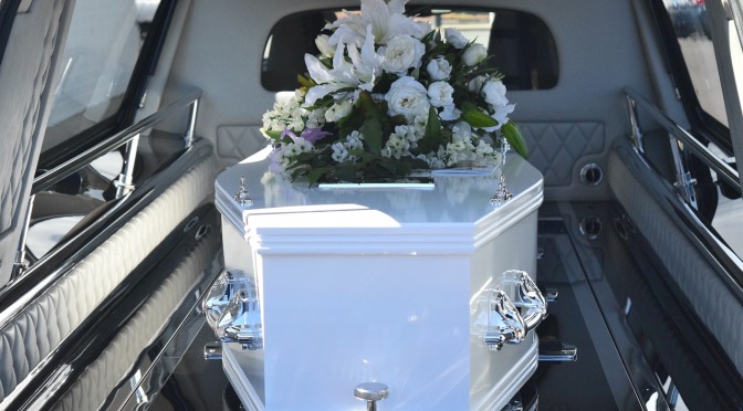 white casket in hearse with flowers